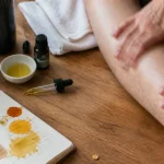 Huile essentielle contracture musculaire : flacon, pipette et application sur le mollet